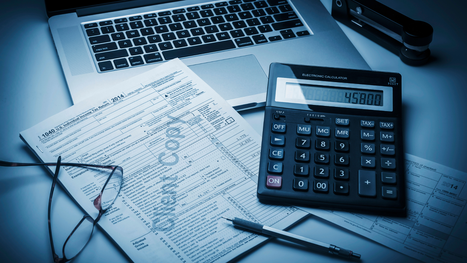 Tax preparation workspace with calculator, laptop and tax documents